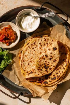 three tortillas on a plate with sauce and lettuce next to it