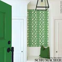 a green door and white bench in front of a wallpapered entryway area