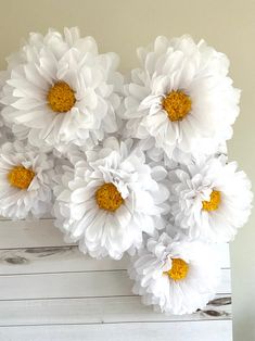 some white and yellow flowers are on a wooden board with wood planks in the background