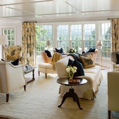 a living room filled with lots of furniture next to a window covered in drapes