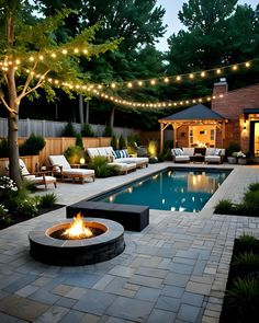 a backyard with a fire pit and seating area next to the pool at night time