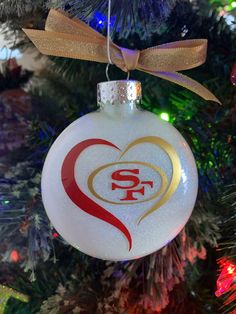 a white ornament hanging from a christmas tree with a san francisco giants logo on it