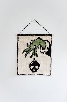 a crocheted wall hanging with an image of a creature on it's face