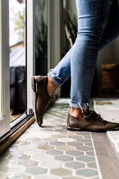 a person standing in front of a door with their feet on the ground and wearing brown shoes