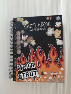 a notebook with stickers on it sitting on top of a white sheet that says sketchbook my friends minor strip