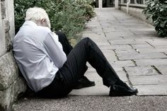 a man with white hair sitting on the ground