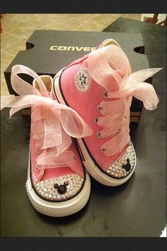 a pair of pink sneakers with bows on them sitting on top of a table next to a box