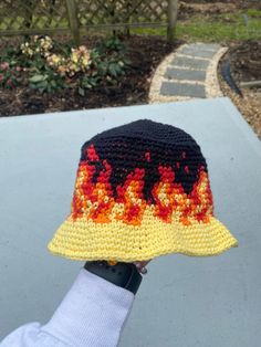 someone is holding up a crocheted hat with flames on it