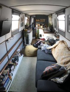 the inside of a camper with couches, bookshelves and television in it