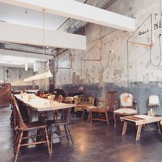 an industrial style dining room with wooden tables and chairs in the center, along with exposed concrete walls