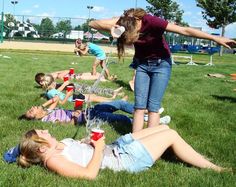 a group of people laying on top of a lush green field next to each other