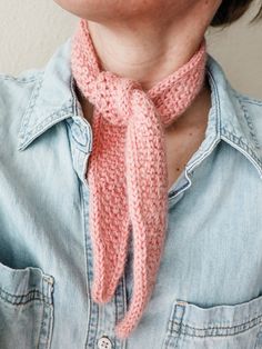 a woman wearing a pink knitted neck tie with buttons on the collar and buttoned down denim shirt