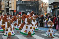 some people are walking down the street in colorful dresses and carrying crosses on their heads