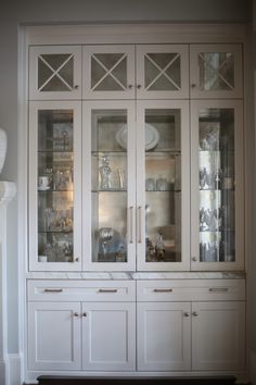 a large white china cabinet with glass doors