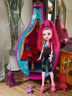 a doll with pink hair is standing in front of a room filled with furniture and accessories