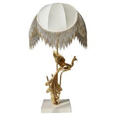 a lamp that is sitting on top of a stand with a bird on it's arm