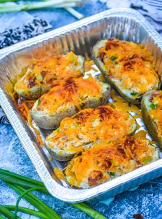 baked stuffed potatoes with cheese and green onions in a baking pan on a blue tablecloth