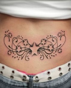 a woman's stomach with stars and swirls on the side, in black ink