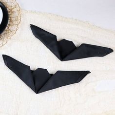 two black paper bats sitting on top of a white blanket