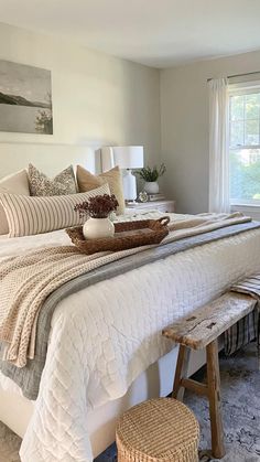 a bedroom with a large bed covered in white blankets and pillows next to a window