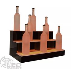 a set of six wine bottles sitting on top of a wooden shelf with black bases