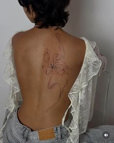 the back of a woman's body with a flower tattoo on her lower back