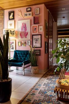 a living room with pink walls and pictures on the wall, including a blue chair