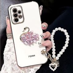 a woman's hand holding a cell phone case with an animal charm on it