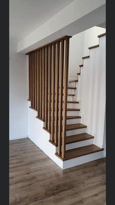 an empty room with wooden stairs and hard wood flooring