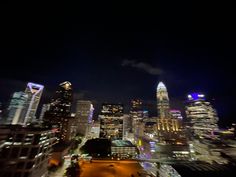 the city skyline is lit up at night with bright lights and skyscrapers in the background