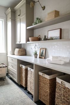 a white counter top sitting under a window next to baskets and boxes on the wall