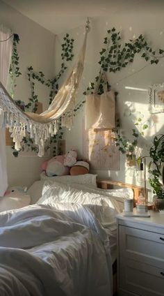 an unmade bed in a bedroom with hanging plants