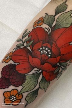 a close up of a person's arm with flowers and leaves on the side