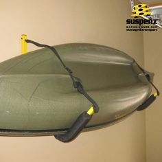 an inflatable boat is hanging from the side of a wall with a yellow handle