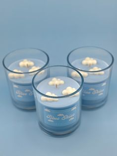 three blue glass candles with small white flowers on the top and one candle in the middle