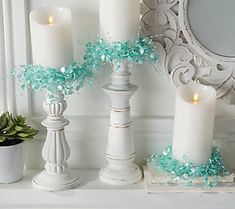 some candles are sitting on a mantle next to a mirror