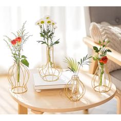 three vases with flowers are sitting on a table in front of a couch and chair