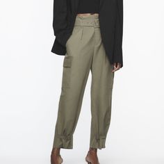 High Waisted Pants With Front Pleats And Self Belt. Front Pockets And Side Flap Patch Pockets. Adjustable Hem With Straps. Front Zip And Metal Hook Closure. Khaki 8277/411 Chic Cargo Pants With Belt Loops, Chic Baggy Cargo Pants, Fall Utility High-waist Parachute Pants, Utility High-waist Parachute Pants For Fall, High Waist Utility Parachute Pants For Fall, Utility High Waist Parachute Pants For Fall, Chic Baggy Cargo Pants For Fall, High Waist Fitted Pants With Belted Cuffs, Fitted Cargo Style Ankle-length Bottoms