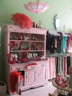 a room filled with lots of pink furniture and umbrellas hanging from the ceiling above it