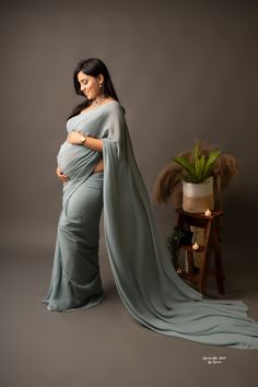 a pregnant woman in a blue dress poses for a photo with her belly wrapped up