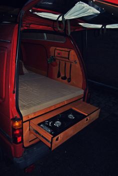 the back end of a red van with an open trunk and mattress in it's cargo compartment