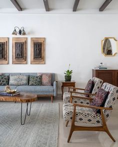 a living room filled with furniture and wooden framed pictures on the wall above it's windows