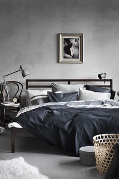 a bedroom with gray walls and black bedding in the middle, white rugs on the floor