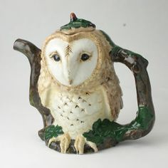 an owl figurine sitting on top of a tree branch