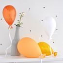 three balloons and two vases on a shelf