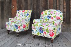 two colorful floral chairs sitting on top of a wooden floor next to each other in front of a fence