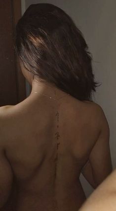 the back of a woman's naked body with writing on her left shoulder and right arm