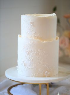 a three tiered white wedding cake sitting on top of a table