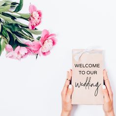 two hands holding a welcome sign with flowers in the background and a bouquet of pink tulips