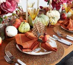 a table set for thanksgiving dinner with pumpkins and gourds